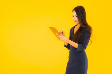 Sarı izole arka planda akıllı tabletli güzel Asyalı kadın portresi.