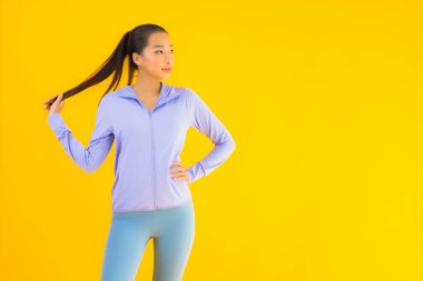 Sarı izole edilmiş arka planda spor giysili güzel Asyalı kadın portresi egzersize hazır.