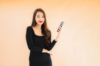 Güzel Asyalı genç bir kadının portresi mutlu bir şekilde gülümsüyor renkli arka planda akıllı cep telefonu kullan