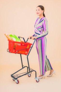 Marketten aldığı alışveriş sepetiyle güzel bir Asyalı kadının portresi. Renkli, izole arka plan.