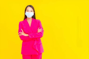 Güzel bir Asyalı kadın koronavirüsü korumak için maske takıyor ya da sarı arka planda 19 numara giyiyor.