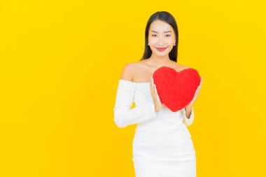 Sarı arka planda, kalp yastığı şeklinde genç ve güzel bir Asyalı kadın portresi.