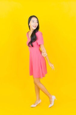 Asyalı güzel bir kadının portresi. Sarı arka planda hareketli gülümsüyor.