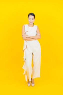 Asyalı güzel bir kadının portresi. Sarı arka planda hareketli gülümsüyor.