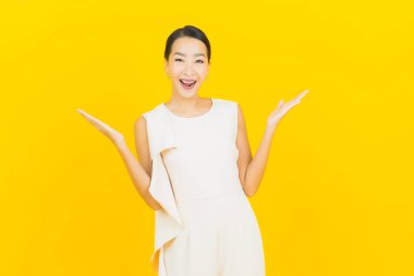 Asyalı güzel bir kadının portresi. Sarı arka planda hareketli gülümsüyor.