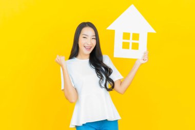 Sarı arka planda ev ya da kağıt tabelalı güzel Asyalı kadın portresi