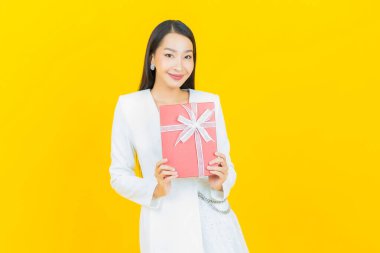 Güzel bir Asyalı kadının portresi. Arka planda kırmızı hediye kutusuyla gülümsüyor.