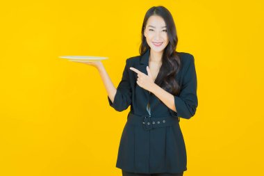 Güzel Asyalı bir kadının portresi. Arka planda boş tabak tabağıyla gülümsüyor.