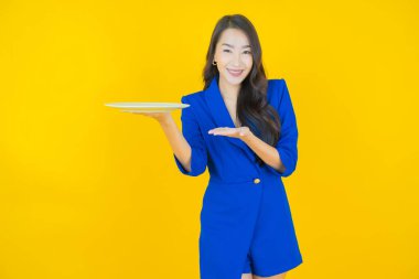 Güzel Asyalı bir kadının portresi. Arka planda boş tabak tabağıyla gülümsüyor.