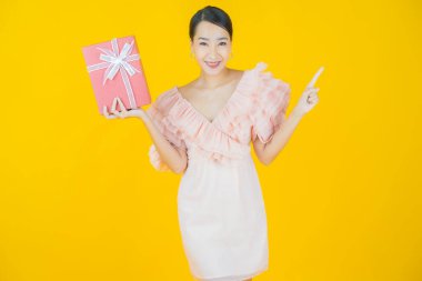 Güzel bir Asyalı kadının portresi. Arka planda kırmızı hediye kutusuyla gülümsüyor.