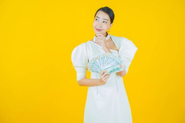 Asyalı güzel bir kadının portresi. Renkli arka planda bol para ve parayla gülümsüyor.