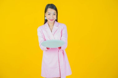 Güzel Asyalı bir kadının portresi. Arka planda boş tabak tabağıyla gülümsüyor.