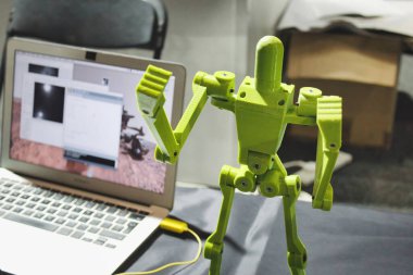Dizüstü bilgisayarın yanında eklemli uzuvları olan 3D baskılı bir robot.