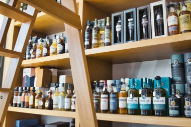 Shelves of premium brand single malt and blended whisky bottles in a specialist liquor store clipart