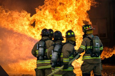 Bir grup ABD 'li itfaiyeci turuncu alevler ve dumanla yanan bir alevle mücadele ediyor