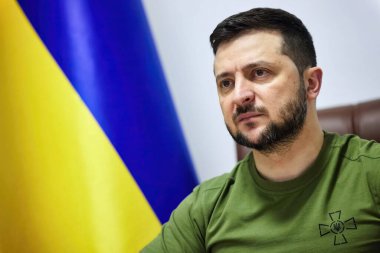 Kiev, Ukrayna - 12 Nisan 2022: Ukrayna cumhurbaşkanı Volodymyr Zelenskyy bir sandalyede oturmuş kameradan, arka planda Ukrayna bayrağı, fotokopi-uzay