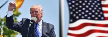 Washington D.C., ABD - 27 Temmuz 2017: Donald Trump siyasi bir mitingde meydan okuma ya da başarı jesti olarak yumruğunu kaldırıyor - arka planda Amerikan bayrağı sallanıyor