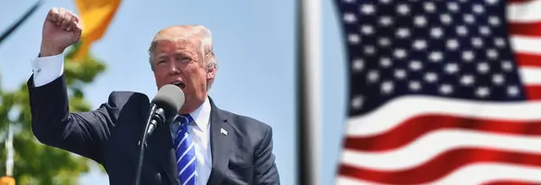 Washington D.C., ABD - 27 Temmuz 2017: Donald Trump siyasi bir mitingde meydan okuma ya da başarı jesti olarak yumruğunu kaldırıyor - arka planda Amerikan bayrağı sallanıyor