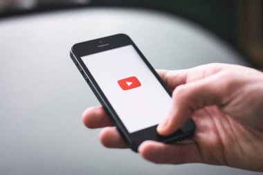 Londra, İngiltere - 27 Haziran 2024: YouTube uygulamasının fotokopi uzayı logosunu gösteren beyaz ekran ile cep telefonu tutan bir elin yakın çekimi