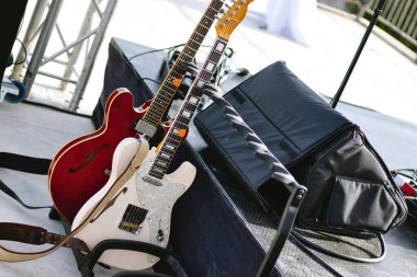 Canlı performans sahnesinin yanındaki tezgaha yaslanmış birkaç elektro gitar.