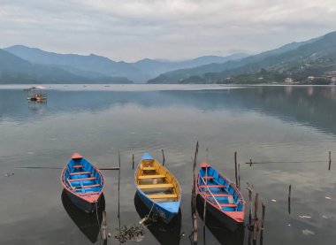 Nepal 'deki Pokhara Vadisi Phewa Gölü boyunca üç renkli tekne.