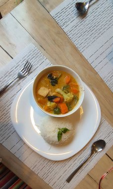 Beyaz bir tabakta beyaz pilav ve körili sarı sebze.