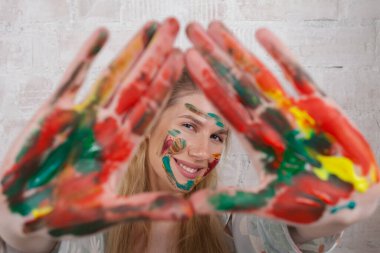 Talented Female Artist smiling happy showing colorful painted hands. Colorful, Emotional, Sensual Painter Creating Abstract Modern Art. Creative Expression concept.