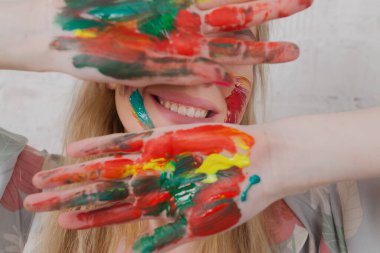 Talented Female Artist smiling happy showing colorful painted hands. Colorful, Emotional, Sensual Painter Creating Abstract Modern Art. Creative Expression concept.