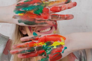 Talented Female Artist smiling happy showing colorful painted hands. Colorful, Emotional, Sensual Painter Creating Abstract Modern Art. Creative Expression concept.