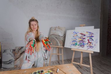 Talented Female Artist smiling happy showing colorful painted hands. Colorful, Emotional, Sensual Painter Creating Abstract Modern Art. Creative Expression concept.