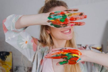 Talented Female Artist smiling happy showing colorful painted hands. Colorful, Emotional, Sensual Painter Creating Abstract Modern Art. Creative Expression concept.