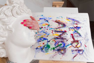 Hand of an artist holding marble head over a painting. Colorful, Emotional, Sensual Painter Creating Abstract Modern Art. Creative Expression concept.
