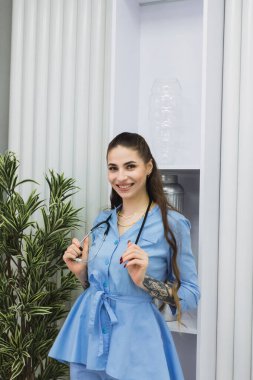 The cosmetic dermatologist is standing with a warm and welcoming smile, putting patients at ease and creating a comfortable atmosphere in her workspace.