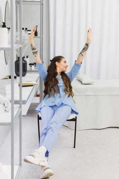 The cosmetic dermatologist takes a brief stretch break while sitting at her desk in this photo.