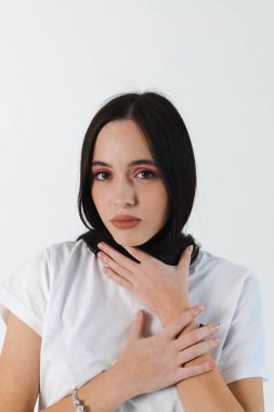 Portrait of a beautiful brunette girl with her hair wrapped around her neck, dressed in a white shirt. Isolated on white.
