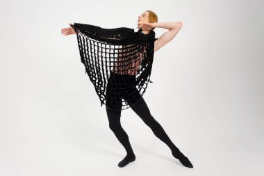 Young Athletic professional ballet dancer with a bare torso and black dance tights in a perfect shape performing over the white background.