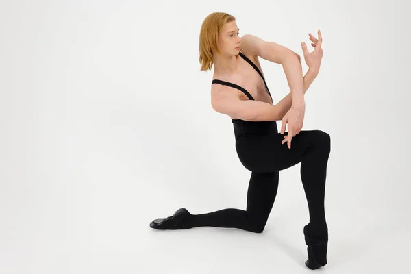 stock image Young Athletic professional ballet dancer with a bare torso and black dance tights in a perfect shape performing over the white background.