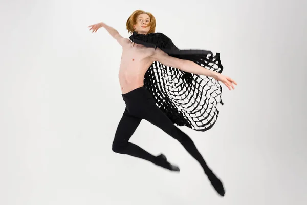 Young Athletic professional ballet dancer with a bare torso and black dance tights in a perfect shape performing over the white background.