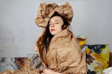 Portrait of a creative young woman wrapped in kraft paper in her creative studio.