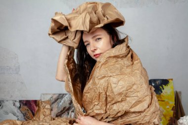 Portrait of a creative young woman wrapped in kraft paper in her creative studio.