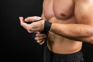 Boxer is wrapping hands with black boxing wraps. Isolated on black background with copy space. Strong hand and ready for fight, active exercise and sparring. Protection Knuckle.