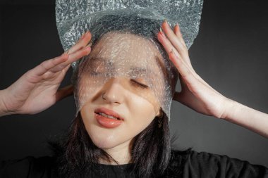 Kafasında plastik torbayla siyah buruşuk elbiseli zavallı bir kızın portresi. Siyah bir arka planda izole edilmiş. Yoksulluk, çaresizlik, acı gerçek..