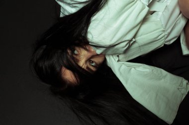 Akıl sağlığı yerinde olmayan ve deli gömleği giymiş bir kadın siyah izole bir arka planda bir akıl hastanesinde yerde yatıyor. Zihinsel bozukluklar konsepti. Çılgın hapishane..