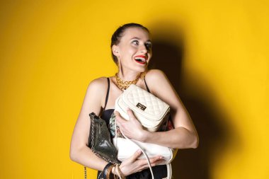 Şehvetli giysiler içinde güzel duygusal bir kadın ve izole edilmiş sarı bir arka plana karşı duran bir el çantası. Mutlu ve heyecanlı ya da şaşırmış