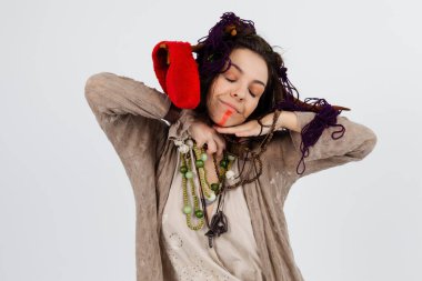 Boynuzlu bir kadın büyücü ya da şaman, beyaz izole bir arka planda tılsımları elinde tutuyor. Şamanik uygulamalar, ruhani ritüeller, Pagan inançları, doğaya ibadet, mistik.