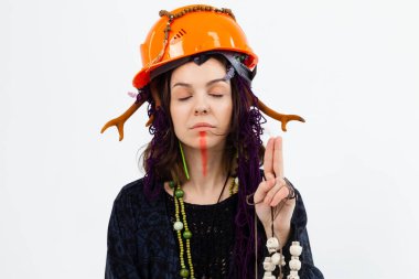 Boynuzlu bir kadın büyücü ya da şaman, miğfer takıyor, beyaz izole bir arka planda tılsımları elinde tutuyor. Şamanik uygulamalar, koruma.