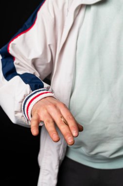 Eşofman giymiş, parmaklarının arasından bozuk para fırlatan bir sokak çocuğunun yakın çekimi. Şehir sokak kültürü, sokak çetesi.