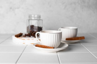 Beyaz arka planda kahve fincanları, kahve çekirdekleri ve tarçın çubukları..