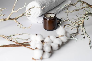Çiçekli pamuk dalı, ağaç dalları, aromatik mum ve beyaz arka planda izole edilmiş beyaz bir havlu. Spa günü konsepti, rahatlama, kendine bakım, doğal güzellik veya organik ürünler.