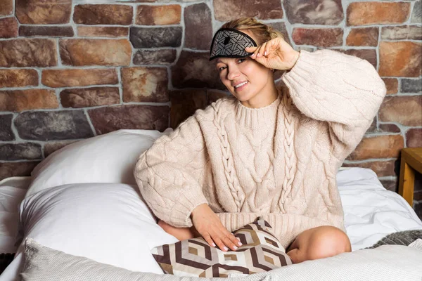 미소짓는 여자가 얼굴에 마스크를 일어나 스웨터를 침대에 — 스톡 사진